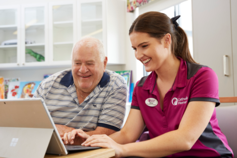 Nurse assisting elderly man with computer at St Vincent's Aged Cared