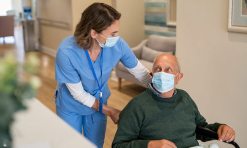 Nurse assisting elderly man in Mask