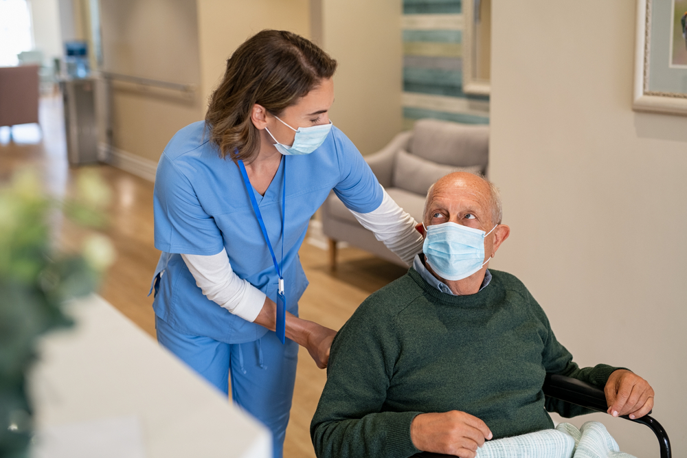 Nurse assisting elderly man in Mask