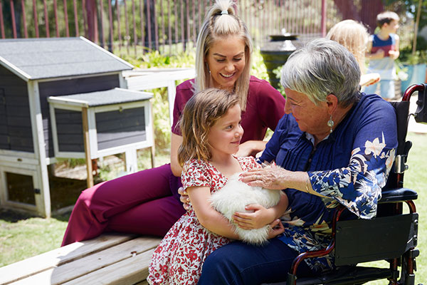 Home care nurse assisting an elderly women who is holding a rabbit