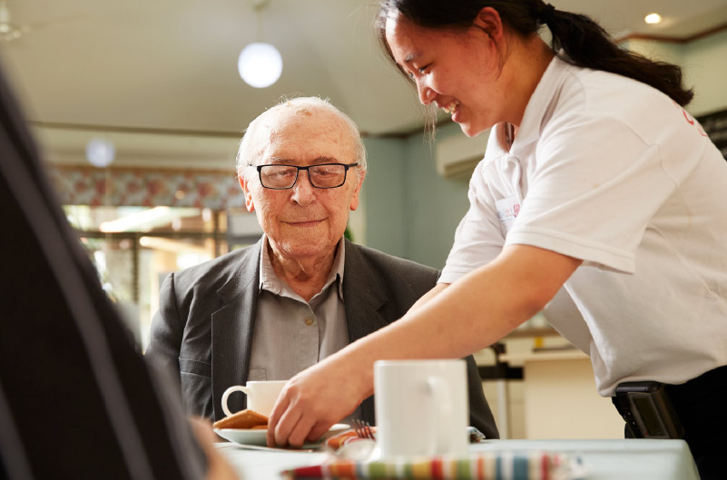 Lady giving a man a cup of team as part of her Hospitality job