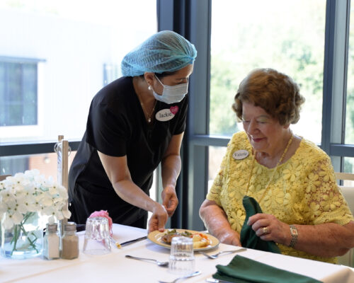 Aged care worker with resident at dinner table