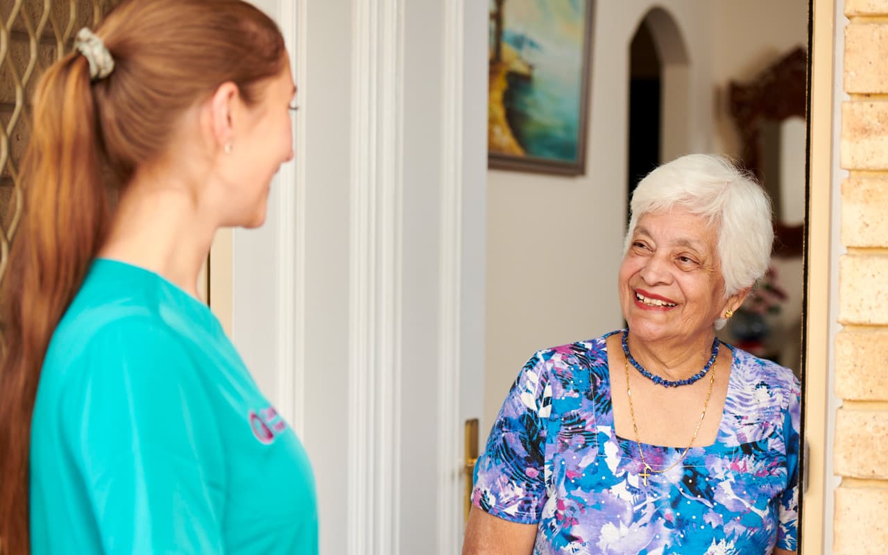 Home Care Support worker greeting a smiling client in her home