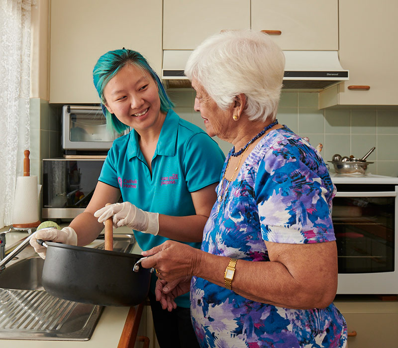 Lady helping elderly lady with food.