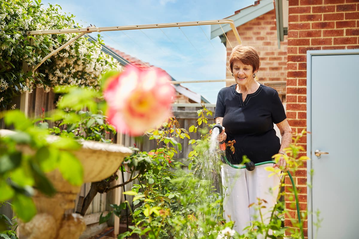 Lady watering her garden at her Independent Living Village in Perth