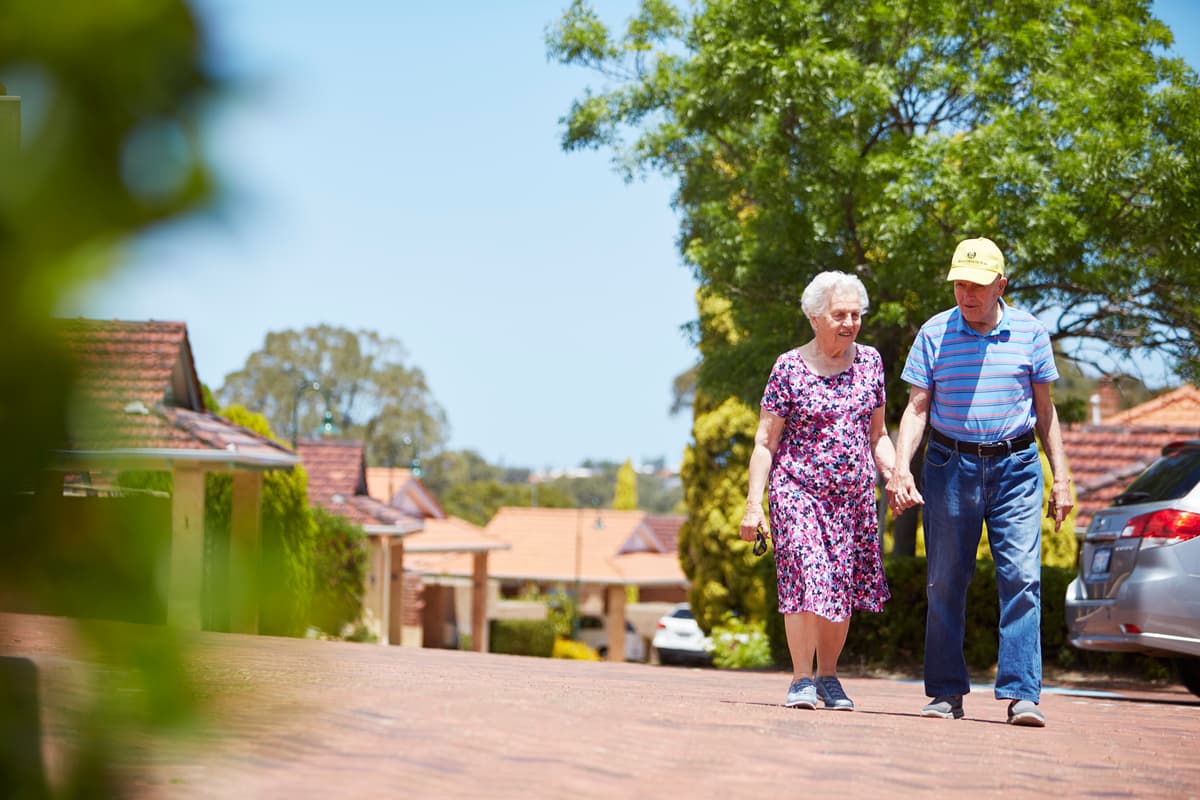 Man and Lady walking together on footpath in Trinity Village Aged Care in Perth