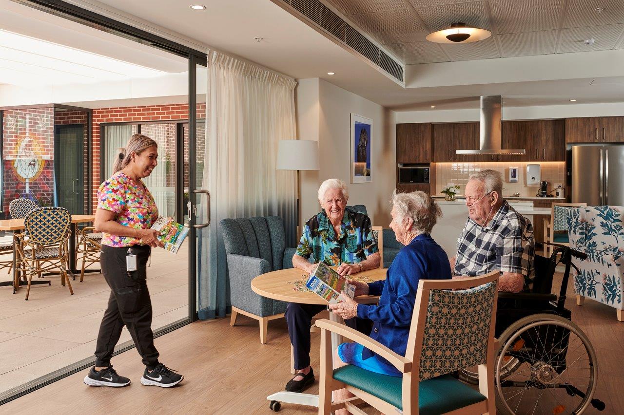 Three happy residents at Sr Mary Glowrey in Belmont talking to a staff member
