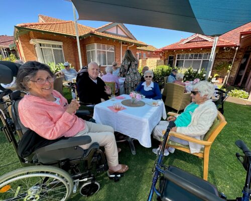 Happy residents around a table at Trinity Village celebrating its recent birthday.