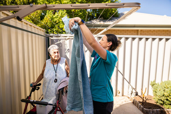 female at home carer hanging out elderly clients washing