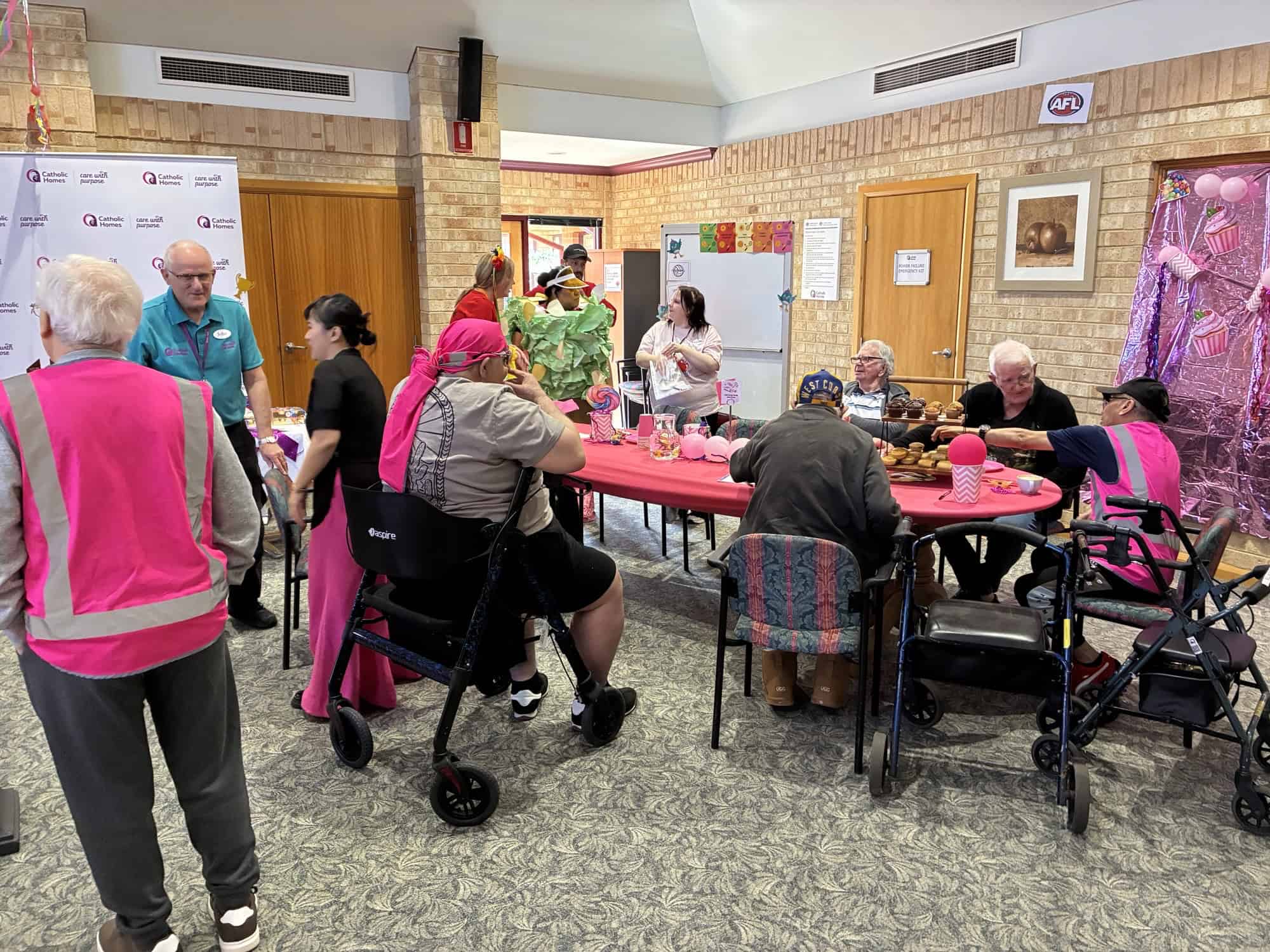 Residents and staff in pink team colours sharing food and laughter at the Catholic Homes Games 2025 at Castledare.