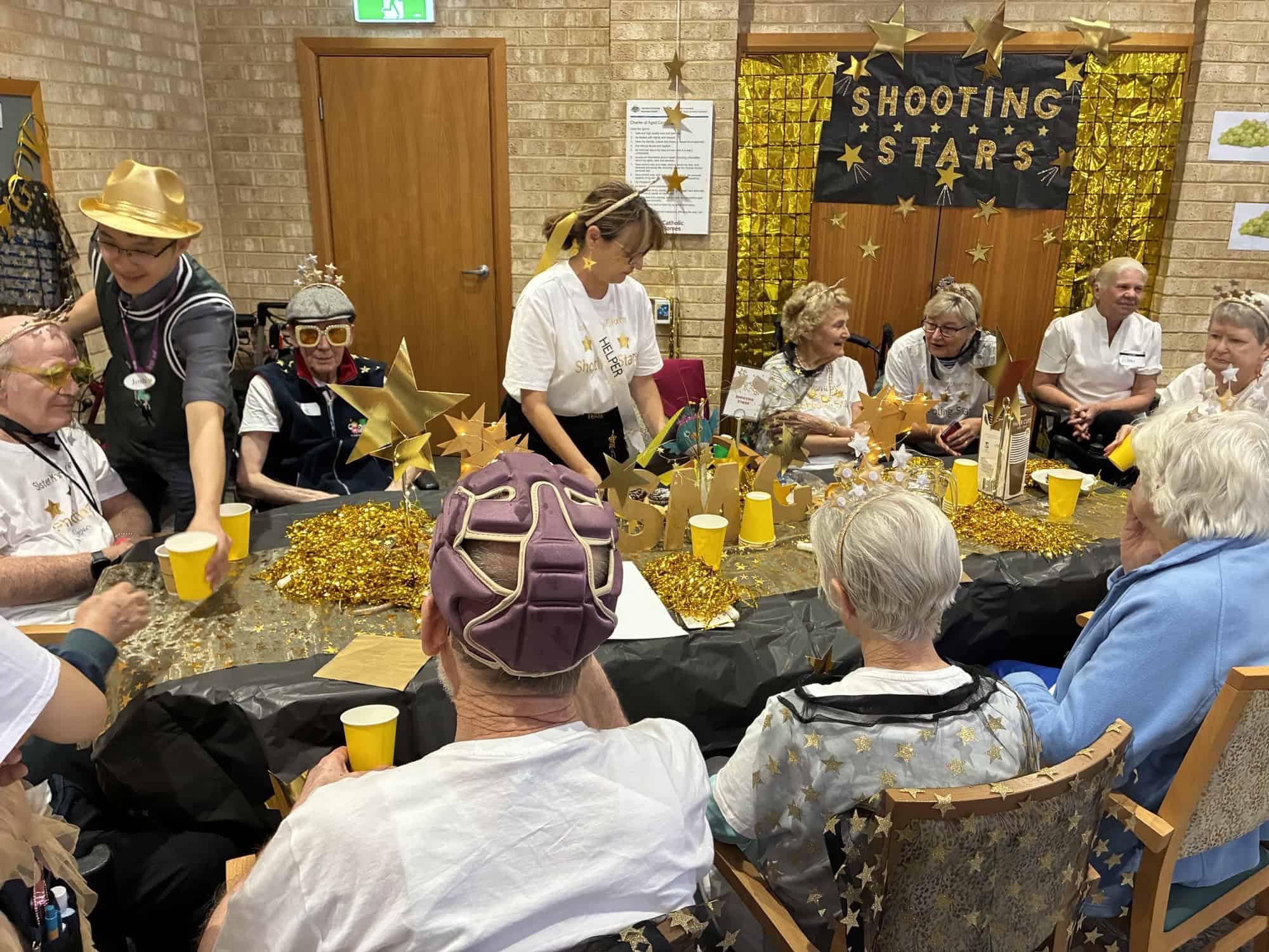 Sister Mary Glowrey residents dressed in gold and stars theme enjoying the Shooting Stars table at Catholic Homes Games 2025.